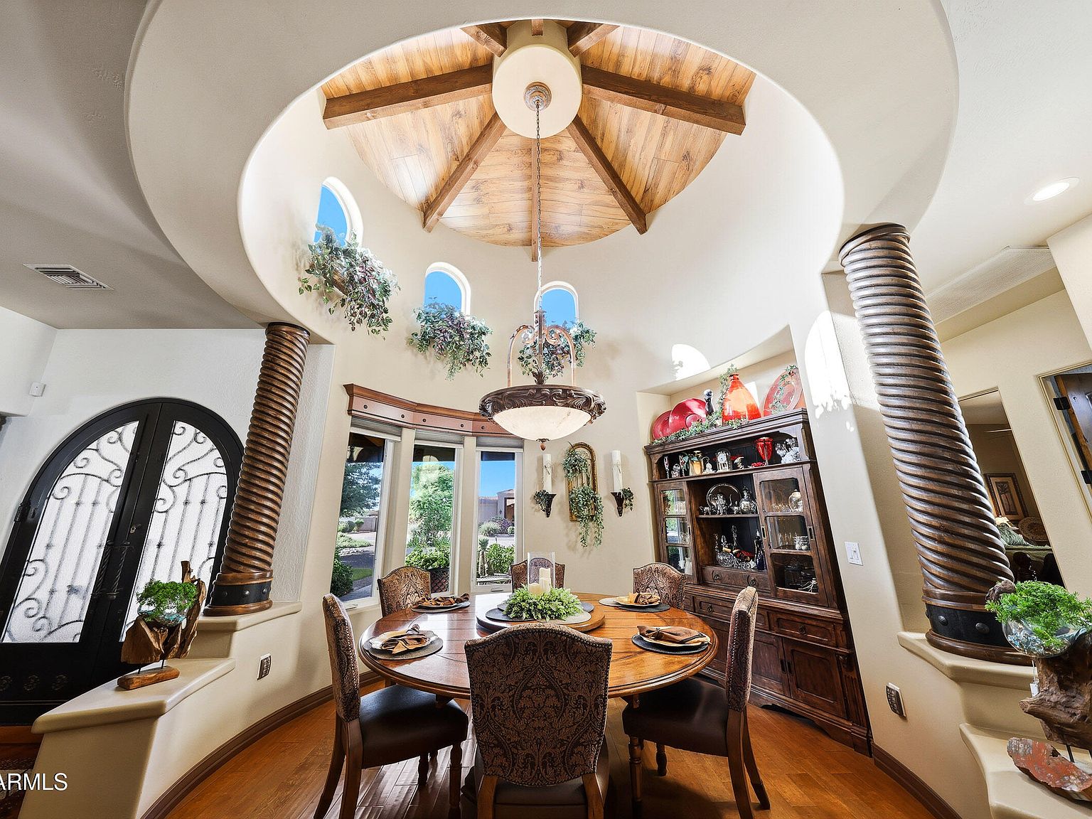 The dining tower with a tall conical wood-beamed ceiling, arched windows on the upper level, twisted-column casings, and a round dining table set for six